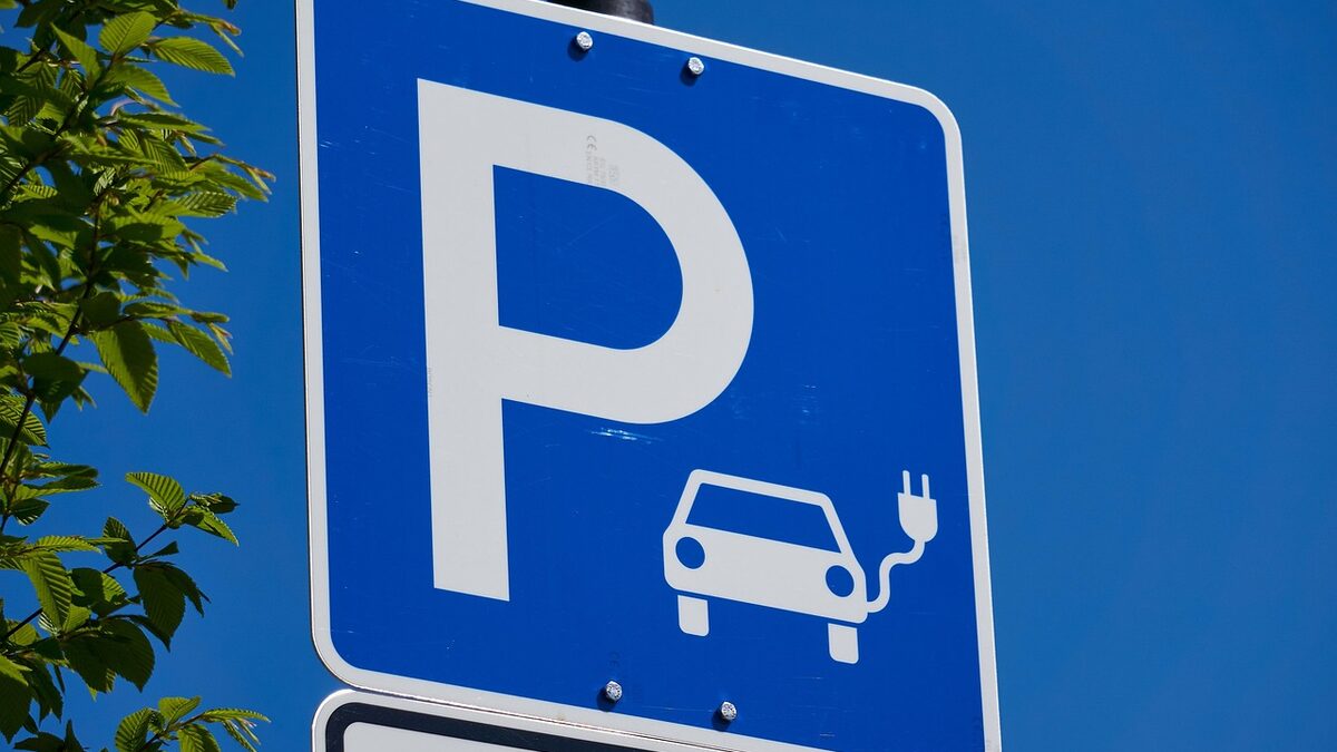 Blaues Parkplatzschild mit dem Sinnbild eines Autos, das über ein Ladekabel mit Strom versorgt wird